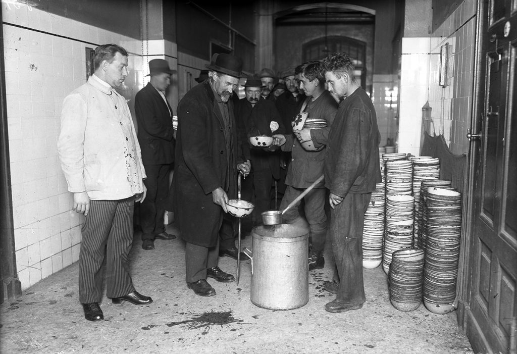 Eine historische Aufnahme zeigt Menschen bei der Armenspeisung in einem Berliner Obdachlosenasyl.